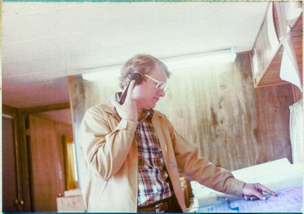 Image 011. Danny Sheffield in the Sheffield Steel field trailer at Space Shuttle Launch Complex 39-B, Kennedy Space Center, Florida. Danny was the son of Dan Sheffield, who owned Sheffield Steel, and he would occasionally pay the jobsite a visit, making sure that all was well, in addition to working liaison with Sheffield’s fabrication shop in Palatka, Florida, if necessary. Here we see Danny on the phone, finger to a blueprint, working some issue or other regarding the structural steel that Sheffield furnished and delivered as their part of the work effort during the construction of the Rotating Service Structure at Pad 39-B. Photo by James MacLaren.